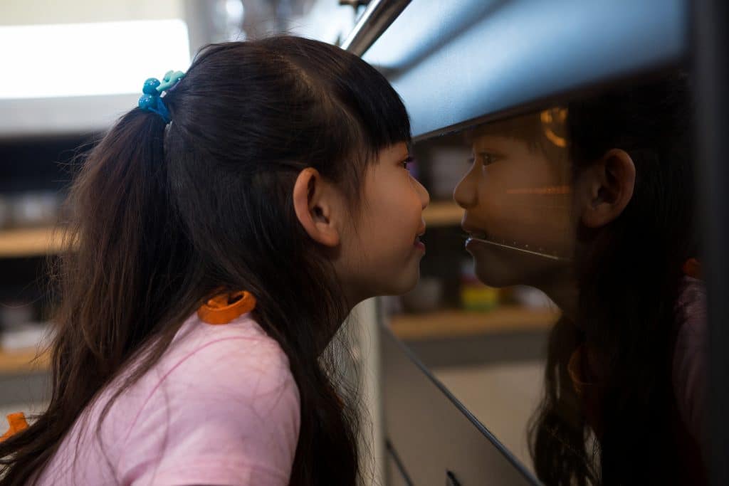 Young girl looking into an oven.